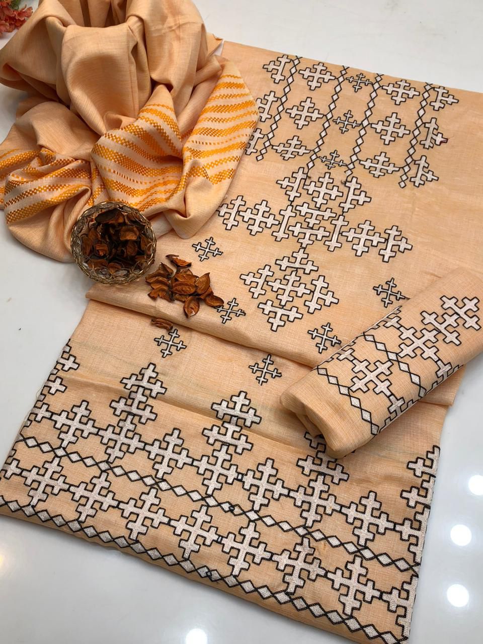 Woman in a beige embroidered outfit standing in an elegant room with lamps and decor.
